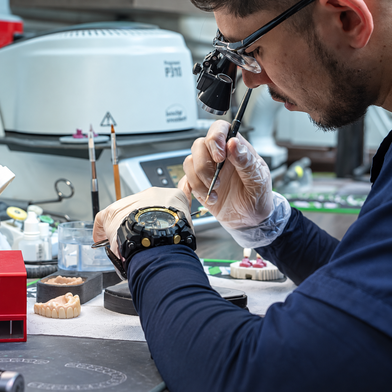 Técnico del laboratorio trabajando con lupas e instrumental dental